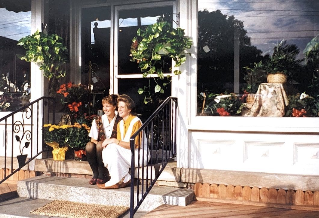 Two women sitting on steps outside a store.