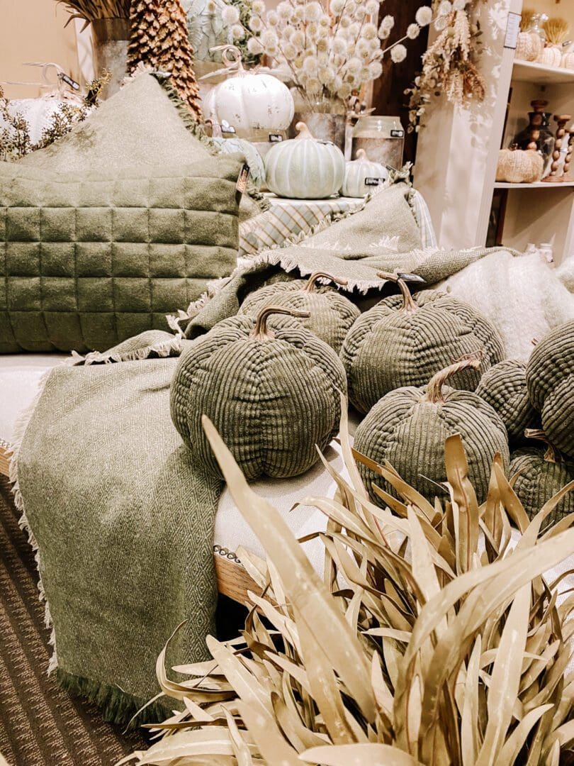 A green couch with pillows and blankets on it.