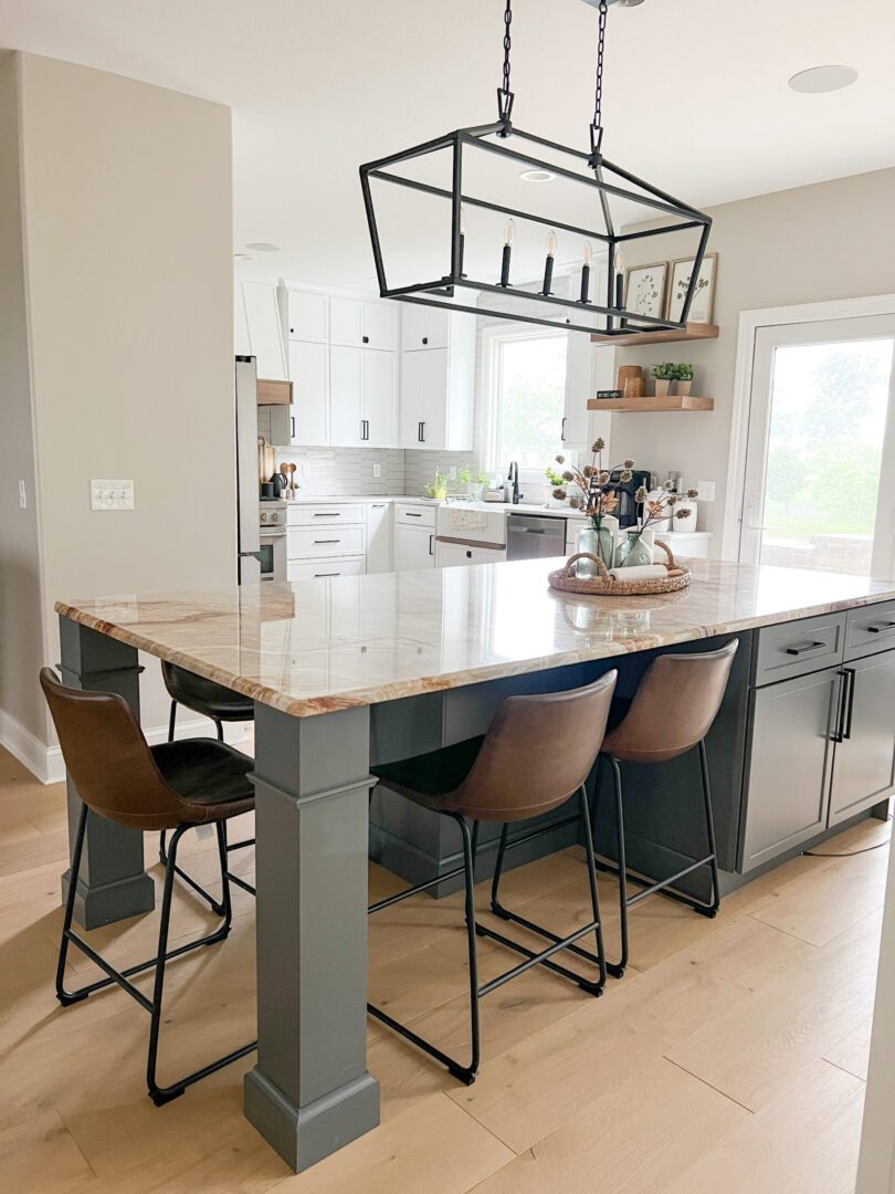 A kitchen with a large island and chairs.