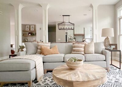 A living room with a couch, ottoman and coffee table.