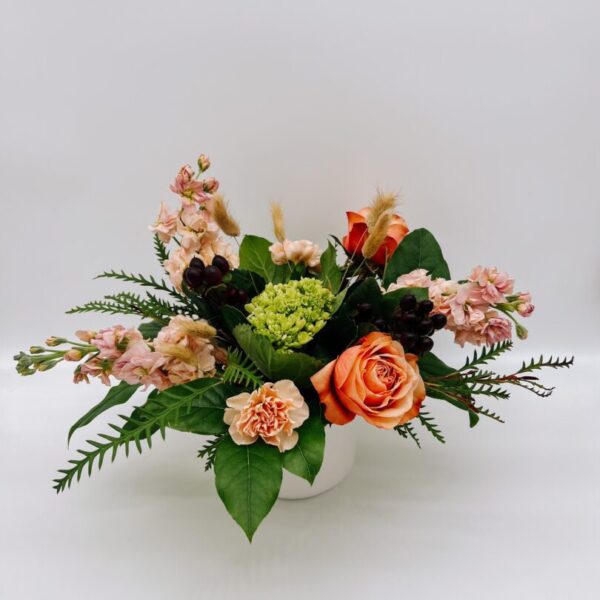 A white vase filled with flowers on top of a table.