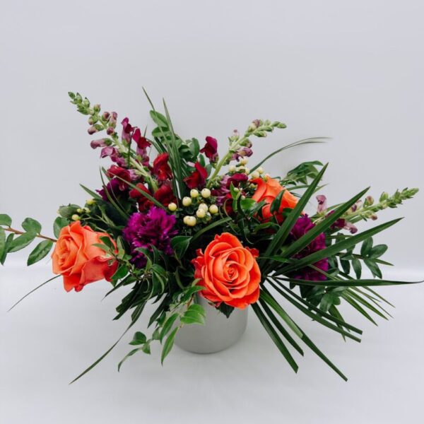 A white vase filled with flowers on top of a table.