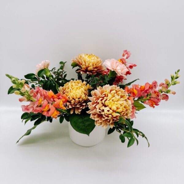 A white vase filled with flowers on top of a table.